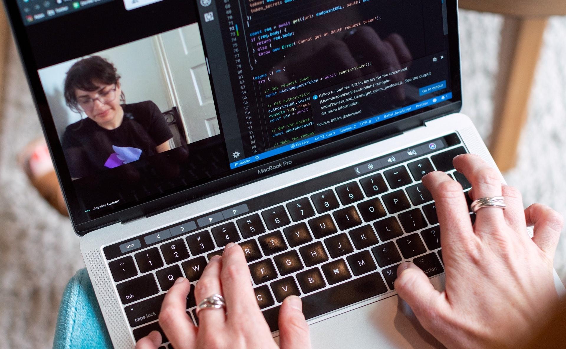 Person typing code on a silver laptop.